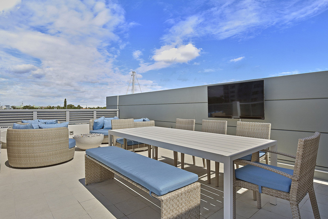 Rooftop terrace with outdoor dining table, wicker seating and wall-mounted TV used as a flex space