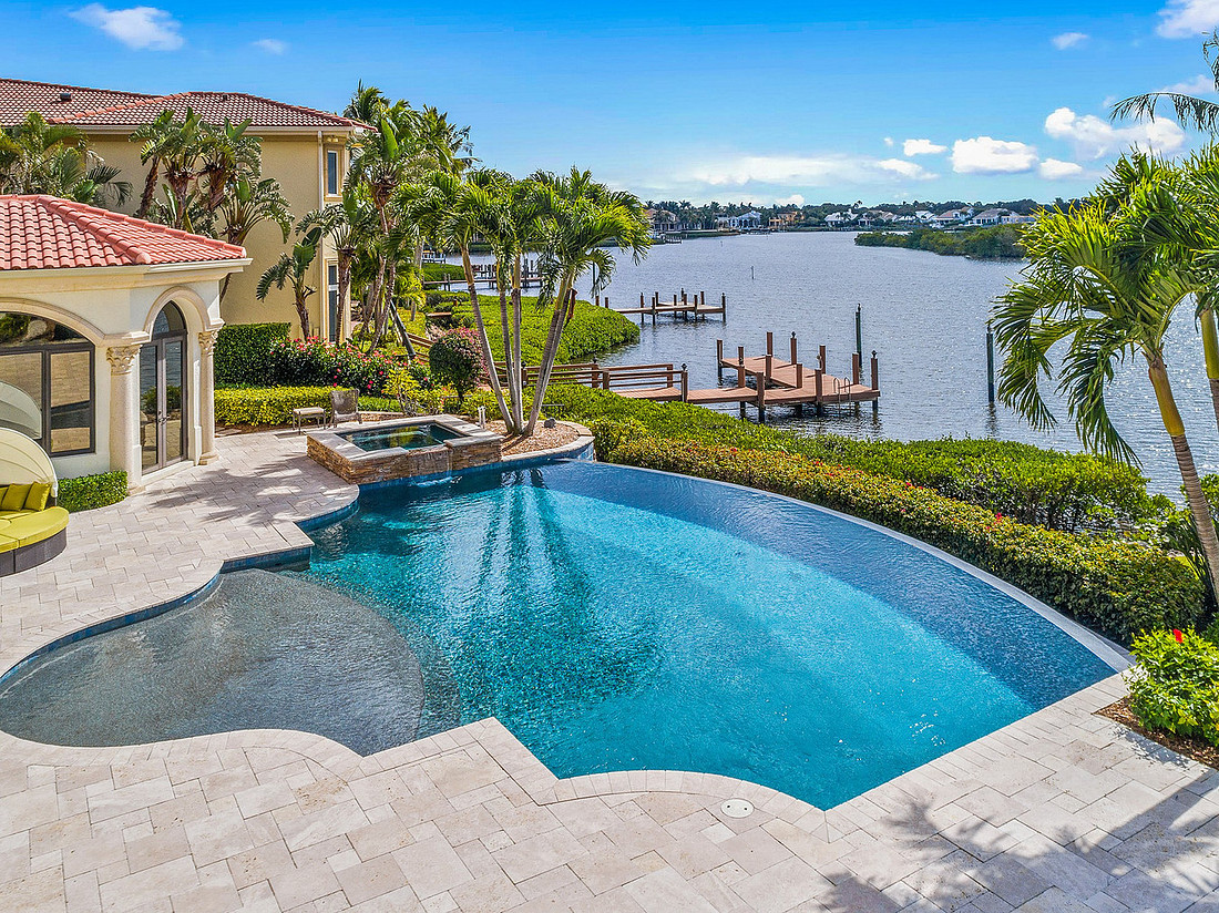 Curved infinity edge pool and spa at a Mediterranean waterfront home with boat docks on the river in Florida