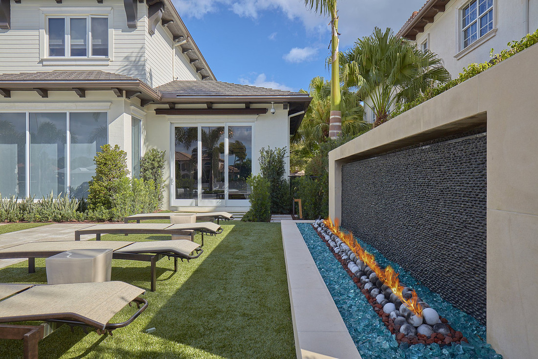 Luxury backyard with stone water wall and linear fire feature, photographed for a Florida real estate listing